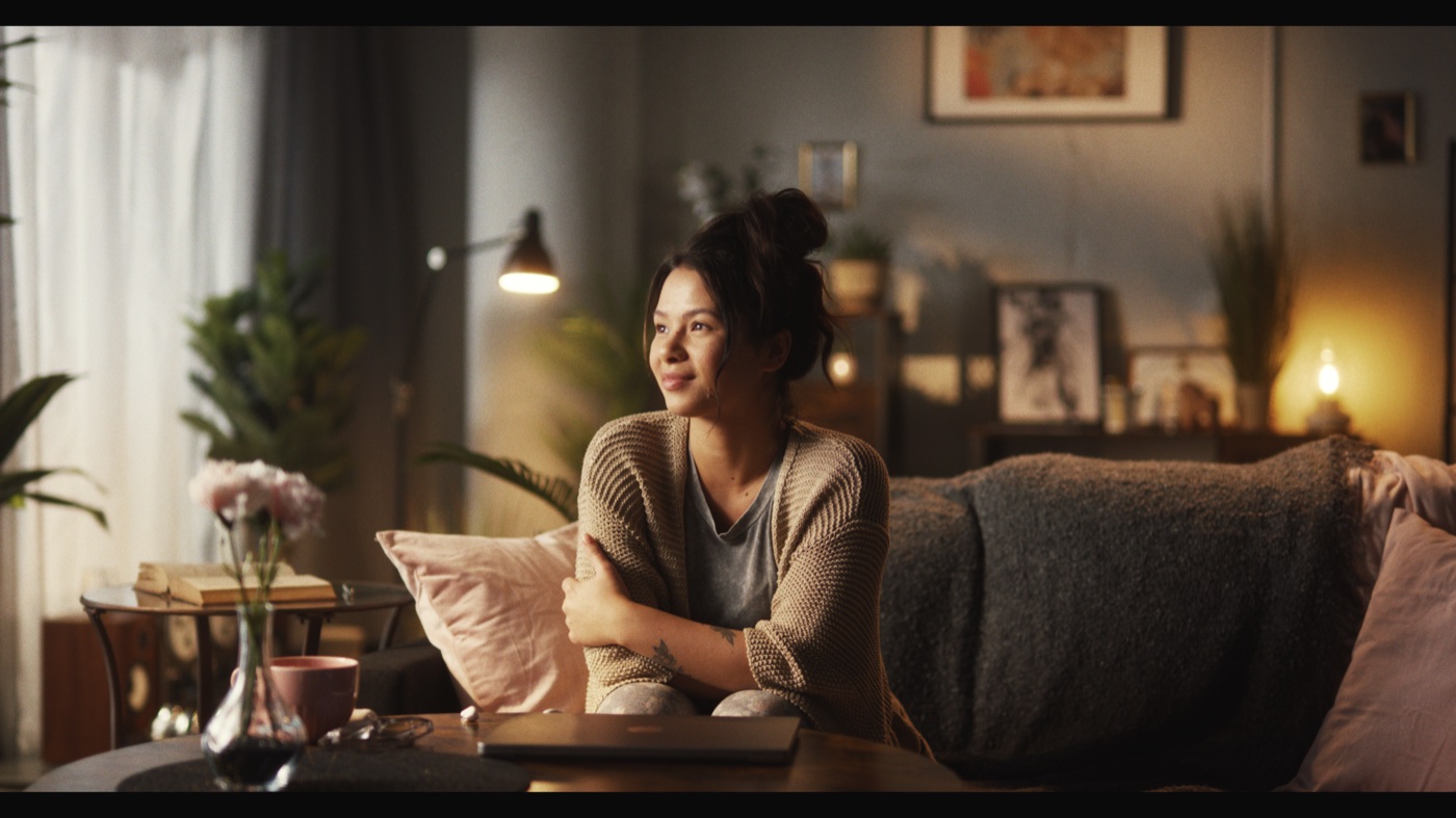 A woman on a sofa in a lamp-lit living room, printed at red 25, green 25, blue 25.
