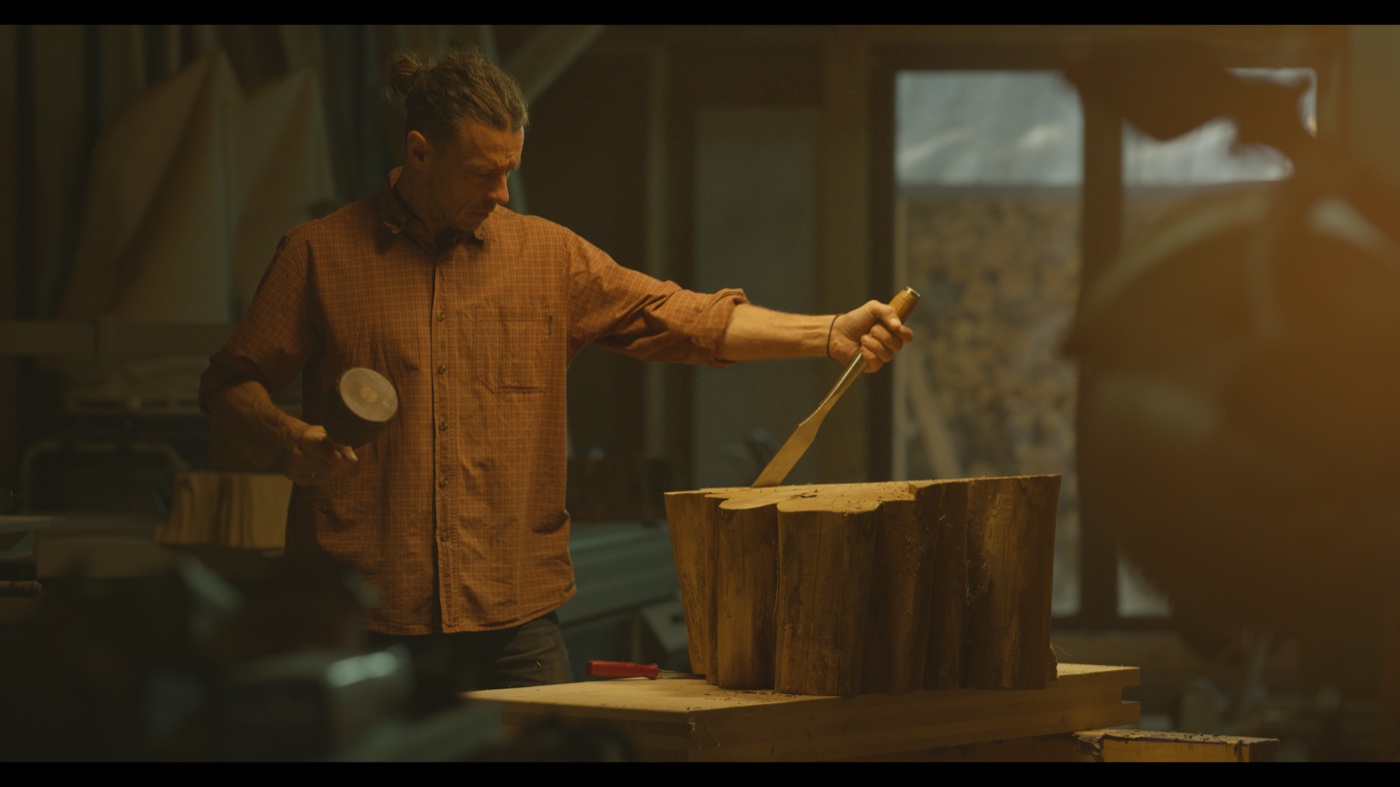 Source frame of a craft worker shaping wood before the Lacerta transform.