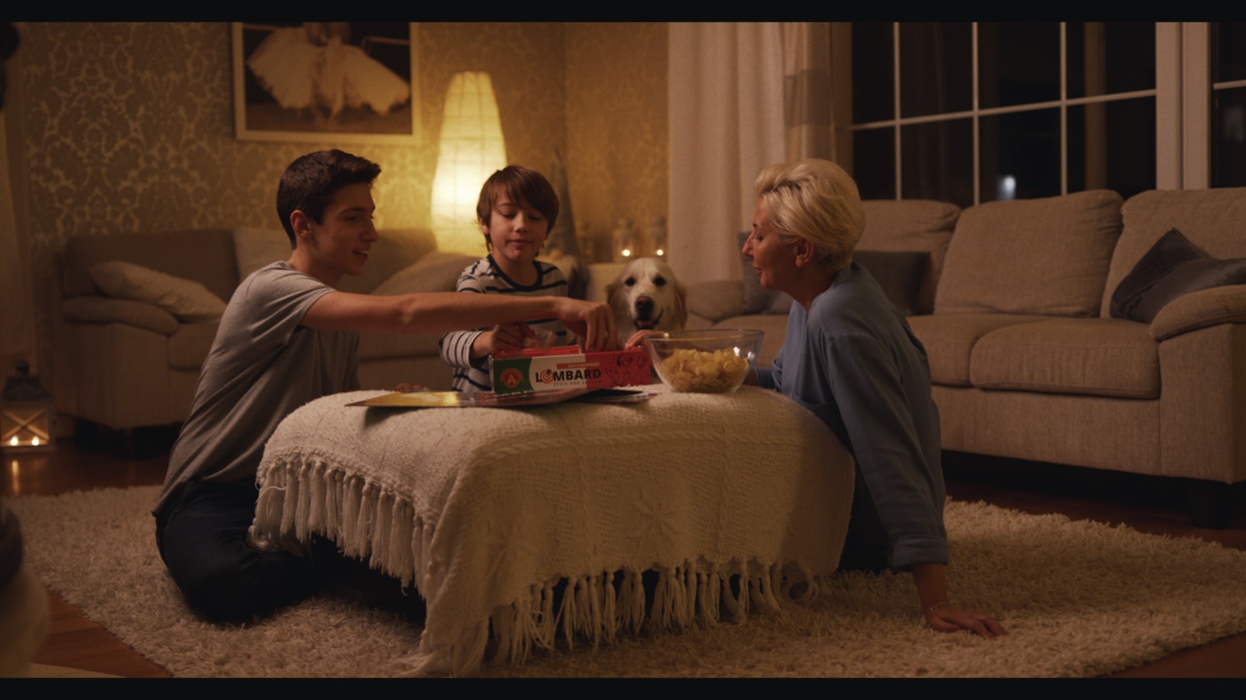A family and their dog playing a board game in a warmly lit living room at night.